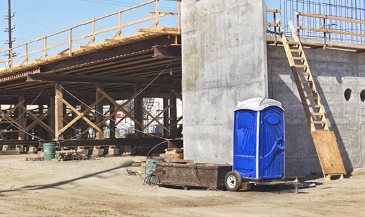 a row of sturdy portable restrooms at a job site